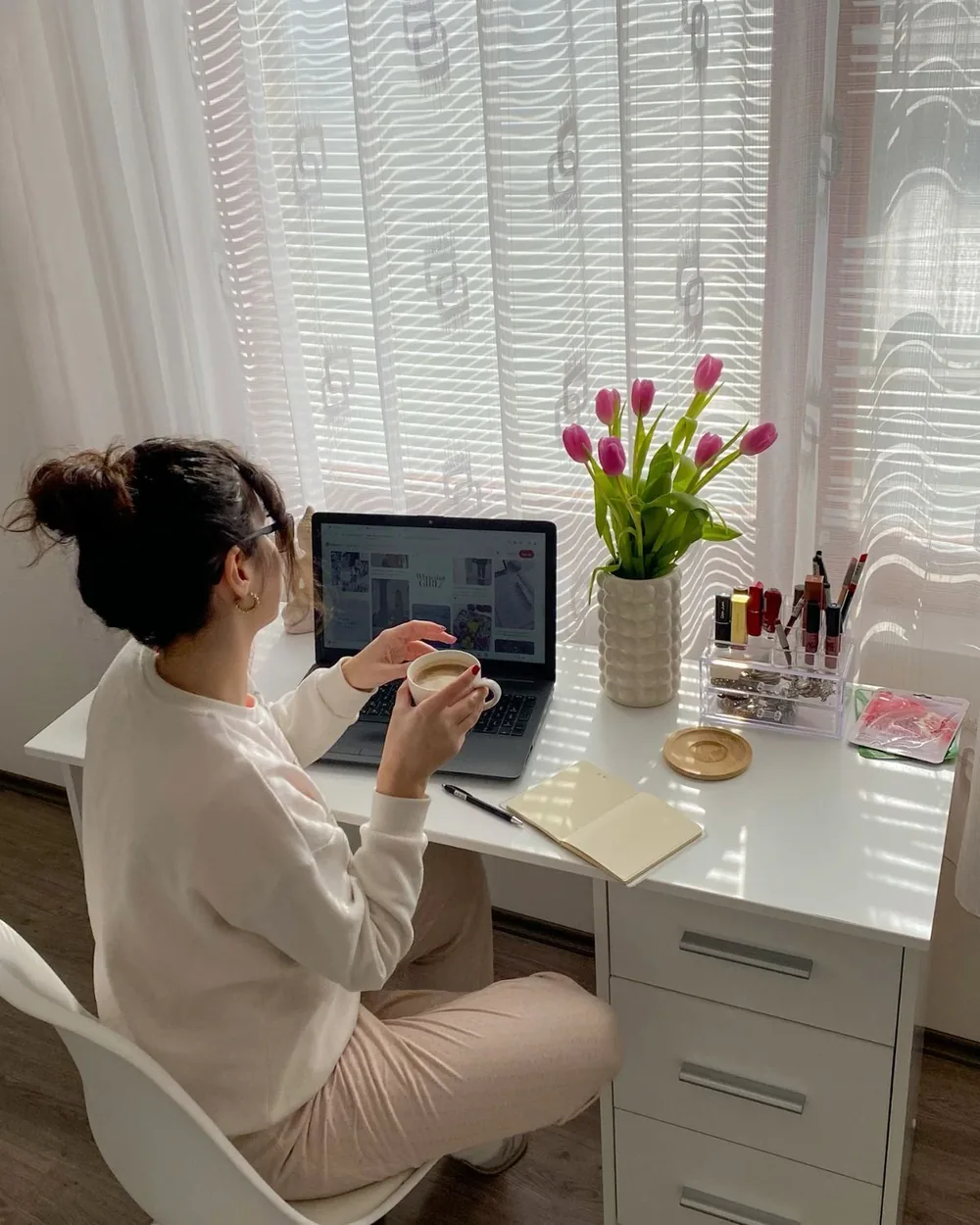 Designer working head-down on a laptop at a sunlit desk